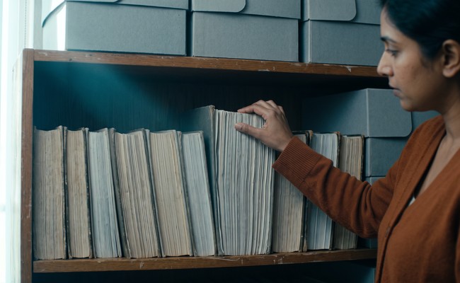 A conservator examining the fore-edges of two volumes held side by side

