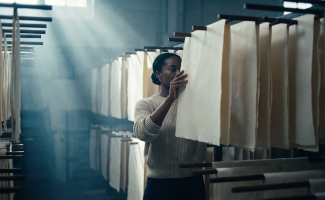 A conservator checking sheets held in a humidity conditioning room
