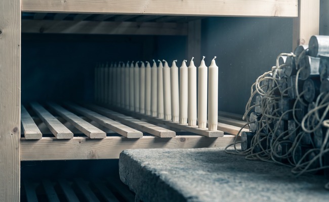 A long rack of identical unmarked candles, none of them labelled or distinguished from any other.