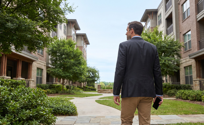 Adult man walking through an apartment courtyard while adapting a working financial plan