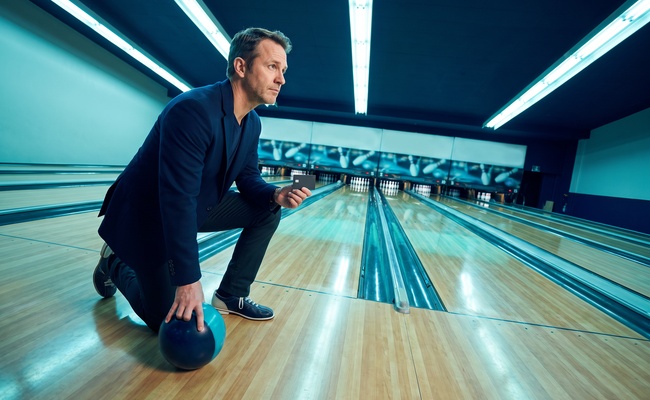 A person pauses beside a bowling ball while weighing the cost of a high-rate card decision.
