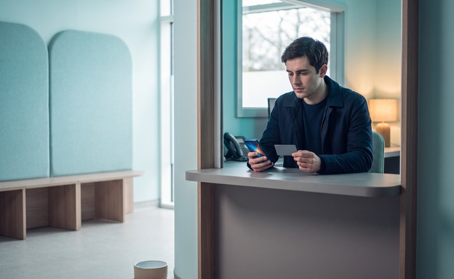 A person checks a plain card and abstract phone in a veterinary-clinic reception alcove after a credit card declined response.