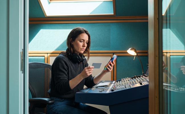 A person verifies a closed card account through a phone call in a recording-studio control room.