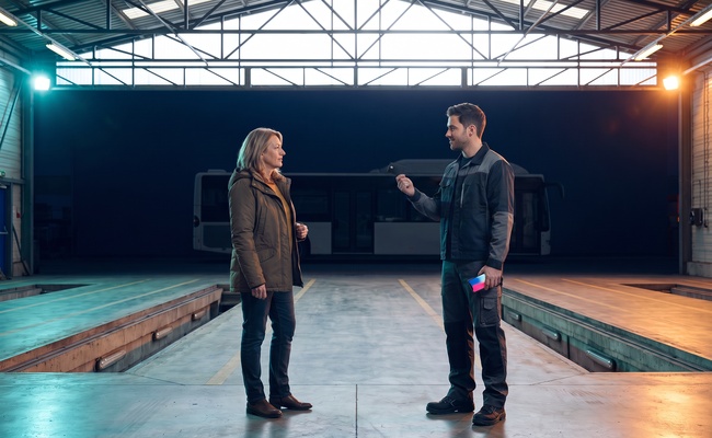Two adults calmly discuss how a closed credit-card account can affect available credit in a bus-depot bay.