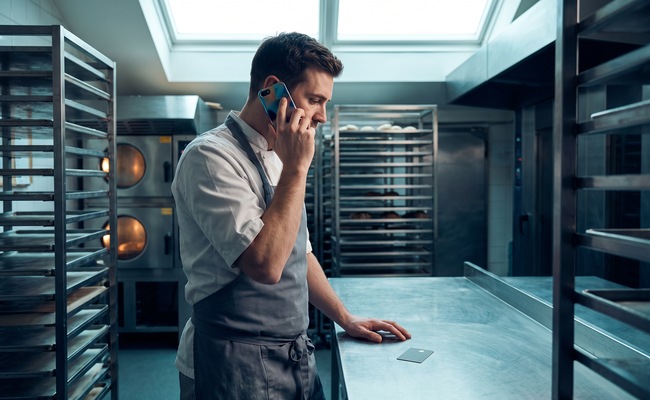 Adult person verifies a reduced credit card limit through a trusted issuer channel in a bright bakery proofing room.