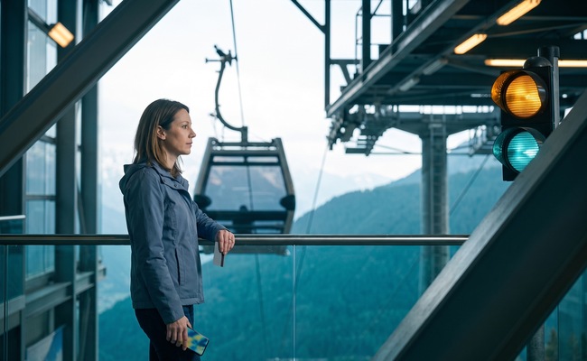 A person studies a phone and asks focused questions after her credit card limit was lowered at a mountain cable-car station.
