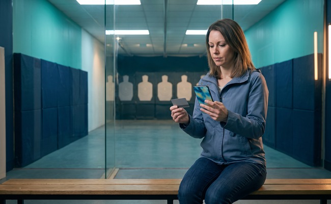 A person weighs a budget choice after her credit card limit was lowered in an indoor archery-range viewing lane.