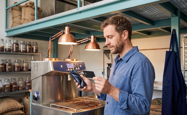 A person reviews the post-promotion rate while learning what happens when a balance transfer expires in an artisanal chocolate tempering room.