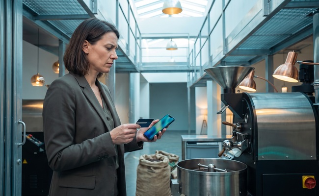 A person prepares a cancellation request for a recurring credit card charge in a small-batch coffee roasting room.