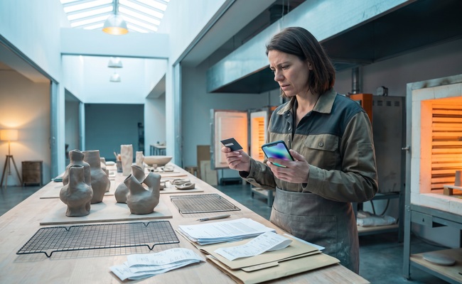 A person organizes evidence for a continuing recurring credit card charge in a community ceramics kiln hall.