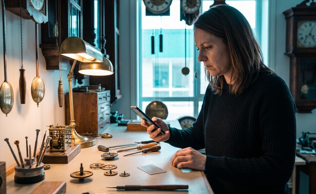 A person adult person studies an abstract phone beside stopped clock mechanisms while checking the facts behind a credit card chargeback vs refund problem.