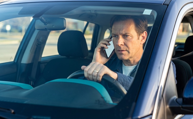 A person adult person considers a hardship plan vs debt settlement arrangement during a careful creditor call inside a parked car.