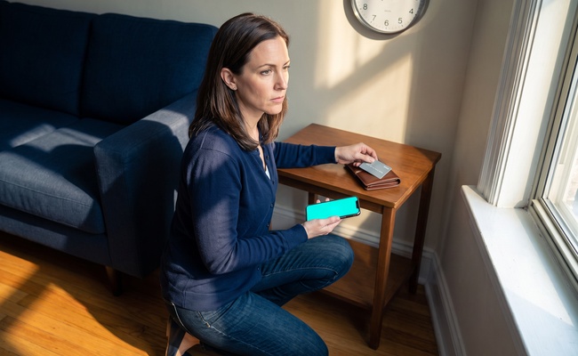 A person adult person checks a blank phone and wallet beside a wall clock while following hardship plan vs debt settlement payment precautions.