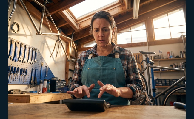 A person adult person compares the cost and benefits of a credit card annual fee in a bright bicycle workshop before deciding whether to negotiate credit card annual fee.
