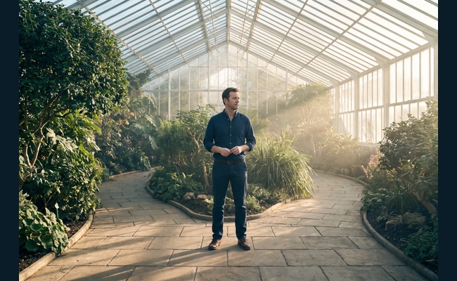 A person adult person considers two paths in a bright conservatory while reviewing whether to negotiate credit card annual fee.