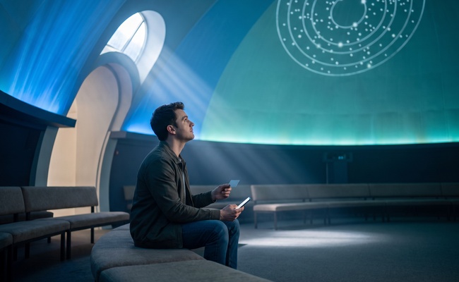 A young adult person distinguishes the statement date from the due date in a bright planetarium foyer before choosing when to pay before the statement closes.