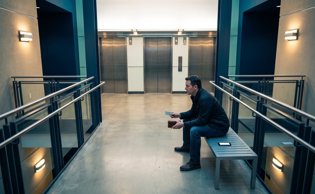 A person weighs whether to leave a credit card overpayment on the account while seated in a bright municipal elevator lobby.