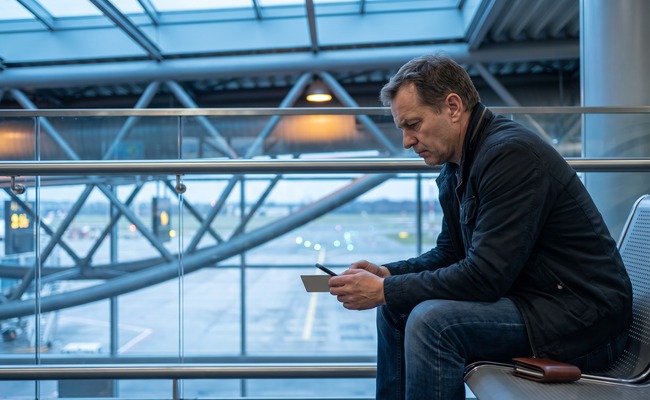 A person adult person compares a blank phone and plain card while distinguishing a reversed credit card payment from a declined or pending status in an airport skybridge.