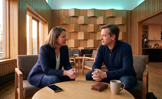 Two adults discuss trace information and resolution for a reversed credit card payment in an orchestra rehearsal hall.