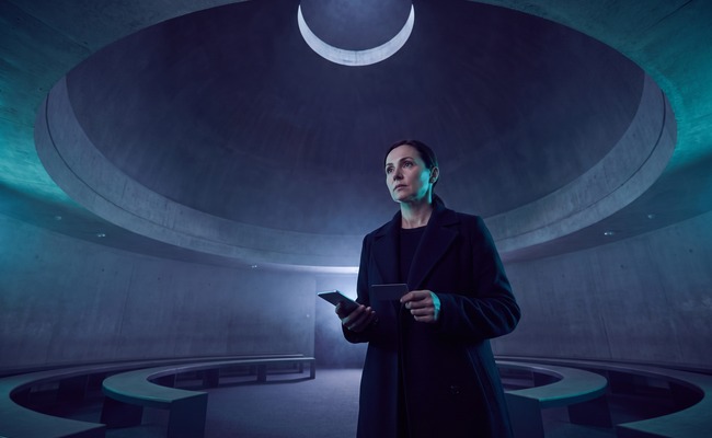 A person adult person considers a pending credit card payment with a blank phone beneath a planetarium dome.
