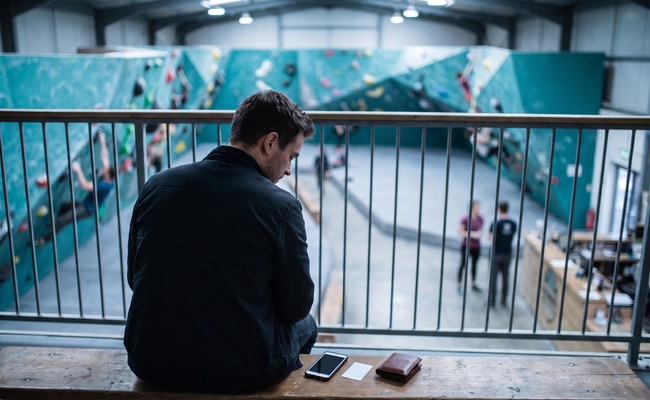 A person adult person considers the fee and credit-reporting effects of a pending credit card payment in a climbing-gym mezzanine.