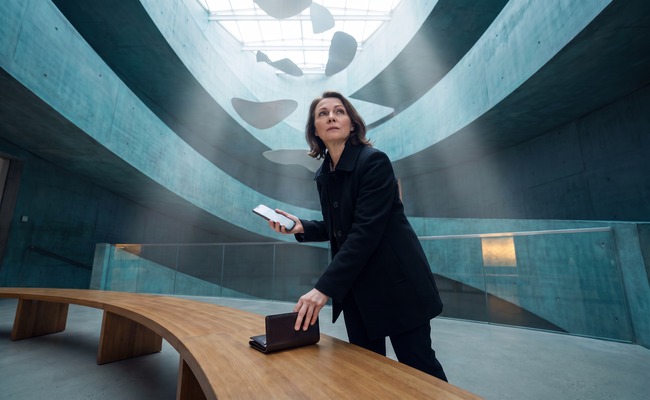 A person adult person considers a change credit card due date plan with a blank phone beneath abstract museum atrium geometry.