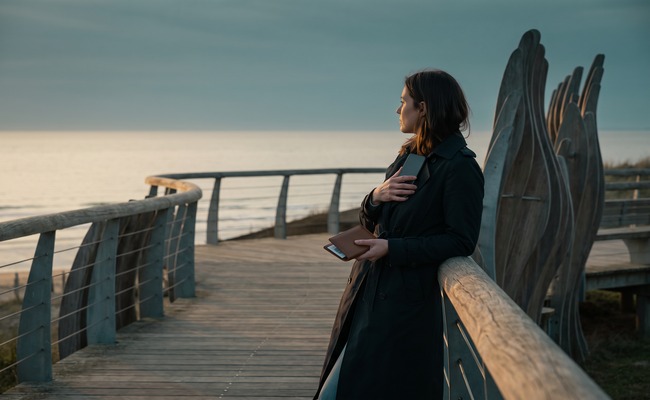 A person adult person waits to confirm a change credit card due date on a blank phone at a coastal boardwalk overlook.