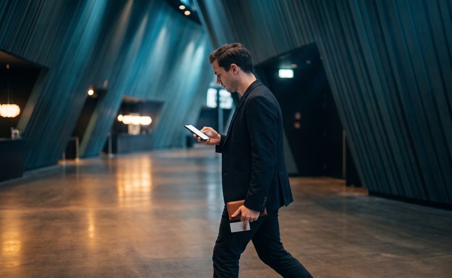A younger adult person reviews a change credit card due date transition on a blank phone in a concert-hall foyer.