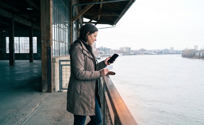 A person adult person at a waterfront warehouse promenade considers weekend timing and her credit card posting time.