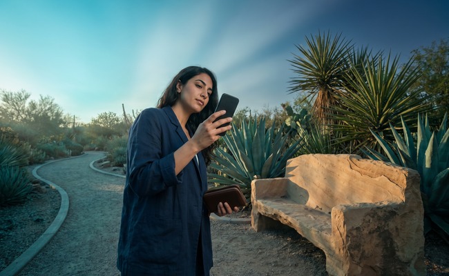 A person adult person evaluates co signer loan risks on a desert botanical garden path with a blank phone and closed wallet.