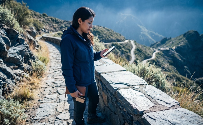 A person adult co-signer reviews release language on a mountain trail while checking a blank phone.