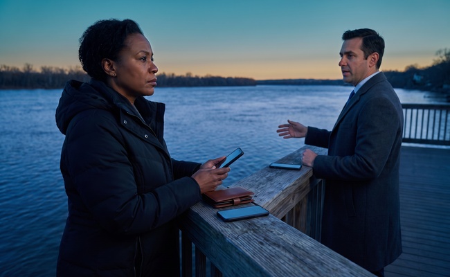 A person adult co-signer discusses legal or credit help with an adviser on a riverside observation deck.