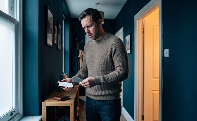 A person notices personal loan origination fees have reduced the cash delivered at a quiet apartment entryway.