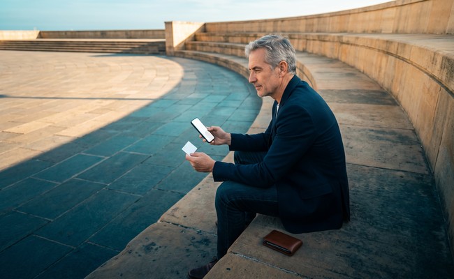 A person older person compares the payoff amount with remaining cost before choosing whether to pay off personal loan early at a civic stairway plaza.