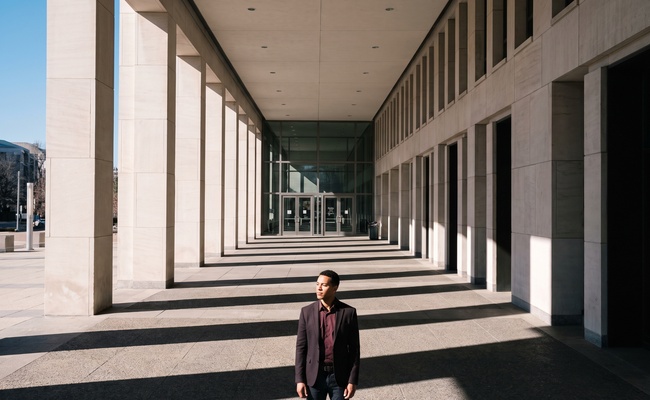 A person informed adult stands beneath a modern courthouse colonnade before asking what records are needed for a deficiency balance.
