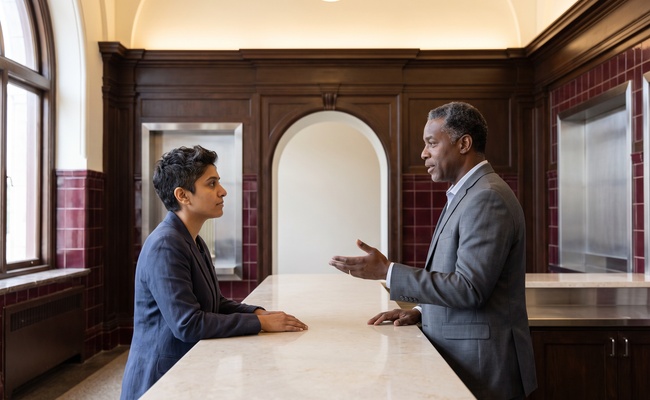 A person adult confirms a belongings pickup procedure with a service representative in a restored station alcove.