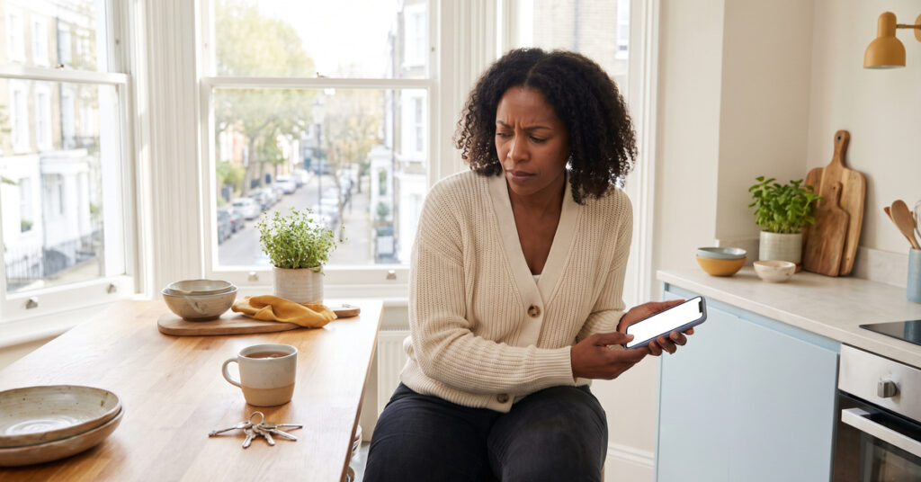 A person homeowner realizing a missed mortgage payment at a bright kitchen counter