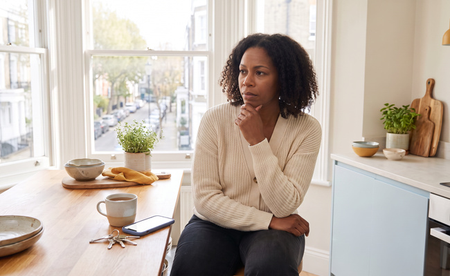 A person homeowner realizing a missed mortgage payment at a bright kitchen counter