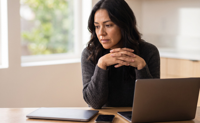A person reviewing a negative bank account balance at a bright kitchen table