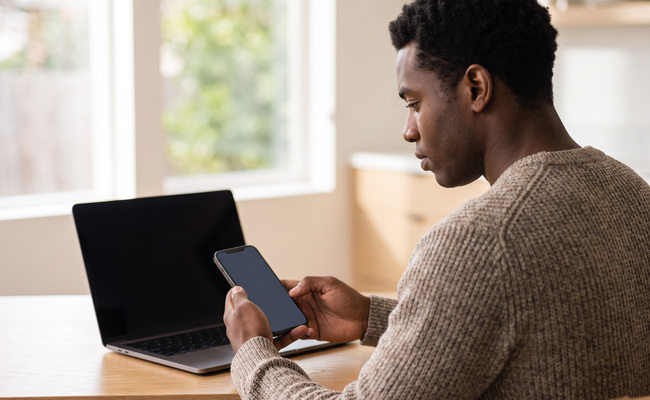 A person reviewing account activity with a blank phone and closed laptop