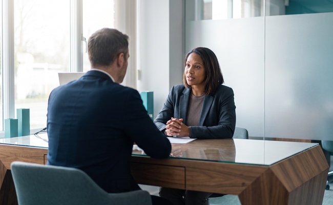 A person speaks with a bank representative at a neutral consultation desk.