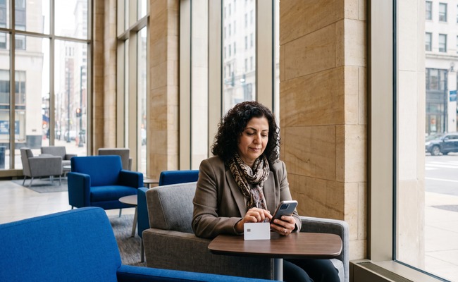 A person-aged adult person reviewing a ChexSystems report with a turned-away phone in a neutral setting