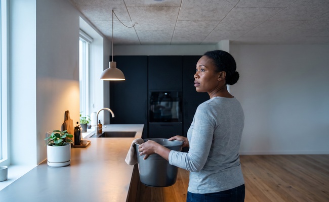A person adult homeowner pauses after a ceiling leak while planning a safer way to pay for home repair without debt.