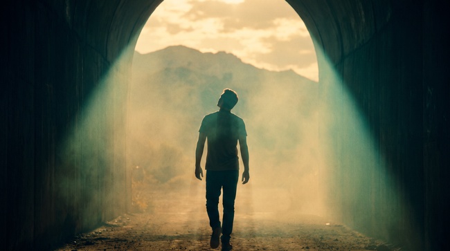 Man walking out of a dark tunnel into bright light symbolizing relief from debt collection stress