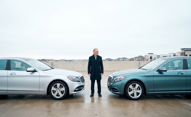 An adult compares two parked cars before making a careful insurance choice.
