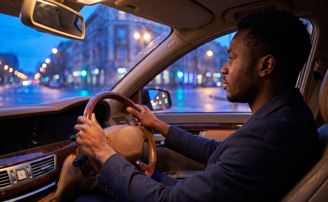 An adult drives calmly through evening traffic while considering safer vehicle habits.