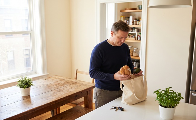 An adult man organizes household finances and groceries while considering a tax lien versus tax levy.