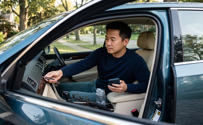 An adult man checks a vehicle key and phone while considering a tax lien versus tax levy.