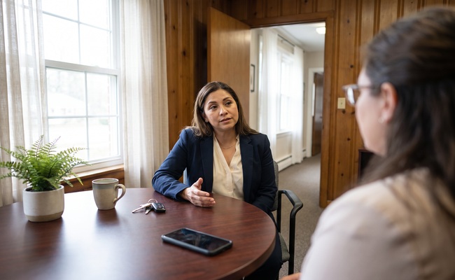 Two women discuss tax lien versus tax levy documents and next steps at a table.