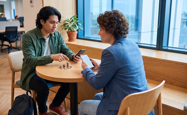 Two people discussing payment timing at a shared table.